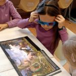 Na fotografii widać dziecko oglądające obrazki w książce w okularach 3d.