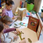 Dzieci układają puzzle 3d z książki smokologia.