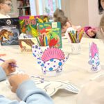 Zdjęcie przedstawia dziewczynki kolorujące dinozaury.