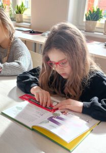 Fotografia przedstawia dziewczynkę czytającą książkę.