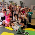 Zdjęcie grupowe uśmiechniętych uczestników spotkania i trzymających ręce w górze.