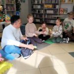 Pan rozdający dzieciom siedzącym w kółku upominki.