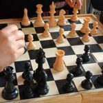 Na zdjęciu widać rozłożone szachy i dziecięce rączki.