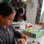 Dziewczynka formuje elementy z plasteliny do gry planszowej.