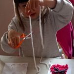 Na zdjęciu dziewczynka wykonuje pracę z włóczki.