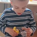 Na zdjęciu widać jak chłopczyk podlewa wodą swoją posadzoną rzeżuchę.