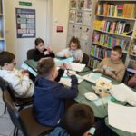 Dzieci wykonują kwiatki wiosenne z kolorowego papieru.