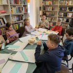 Dzieci wykonują kwiatki wiosenne z kolorowego papieru.