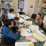 Dzieci wykonują kwiatki wiosenne z kolorowego papieru.