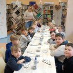 Zdjęcie przedstawia dzieci siedzące przy stole i Panią Dyrektor.