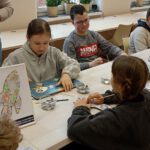 Fotografia przedstawia dzieci i dziewczynkę czytającą książkę.