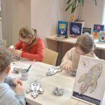 Zdjęcie dzieci siedzących przy stole i wykonujących pracę.