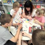 Dzieci wraz z mamaą składają klocki lego